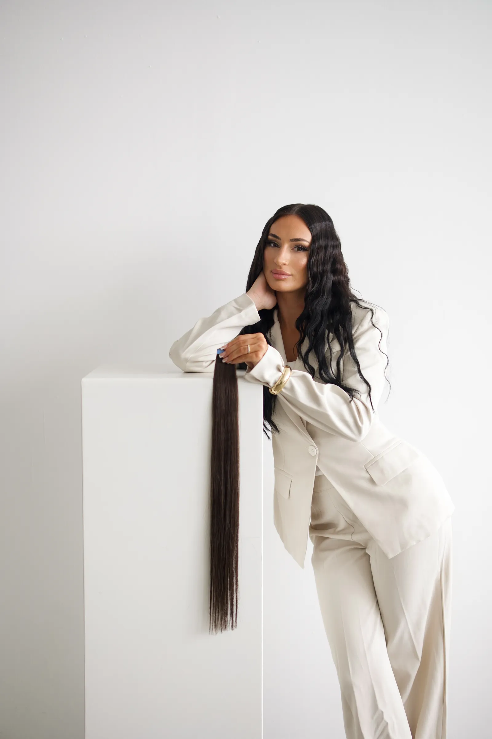 Leyla, Friseurmeisterin und Inhaberin von LEYLABEAUTY in Troisdorf, im cremefarbenen Anzug mit Tape-In-Extensions